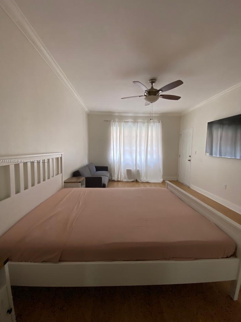A bedroom features a large bed, a ceiling fan, a sofa, and white curtains — 1227 Euclid Ave # 6, Miami Beach FL 33139, MIAMI BEACH, FL