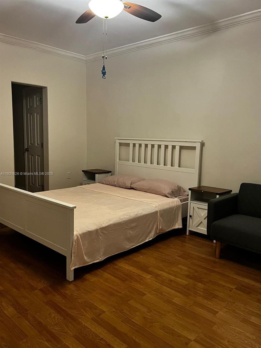 A bedroom features a white bed frame, two nightstands, and a dark armchair on wood flooring — 1227 Euclid Ave # 6, Miami Beach FL 33139, MIAMI BEACH, FL