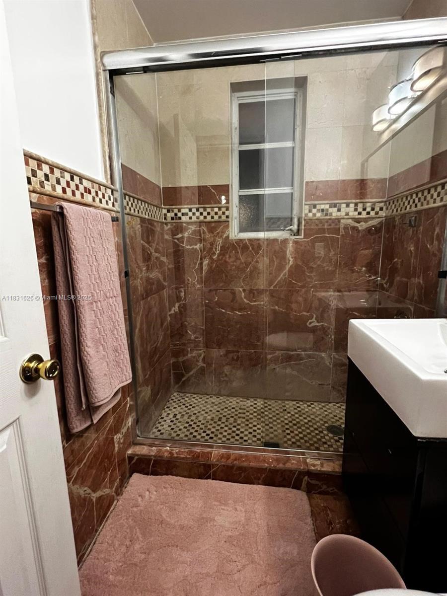 A bathroom features a glass-enclosed shower with brown marble-look tiles and a checkered accent border — 1227 Euclid Ave # 6, Miami Beach FL 33139, MIAMI BEACH, FL