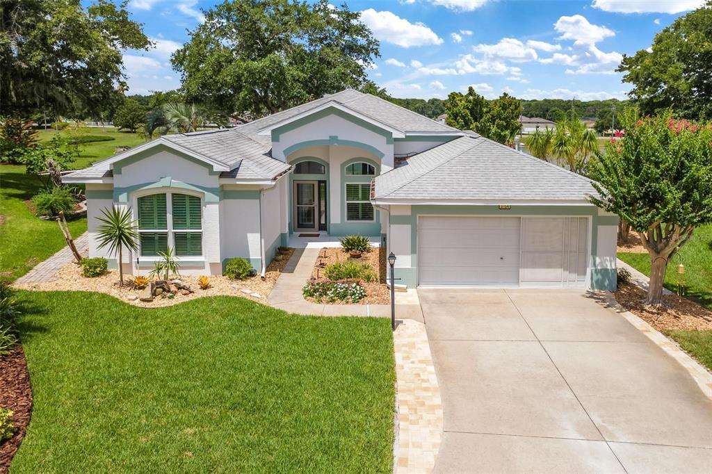 A single-story house with a white stucco exterior, green trim, and a two-car garage — 3354 SAINT LUCIA COURT, TAVARES, FL