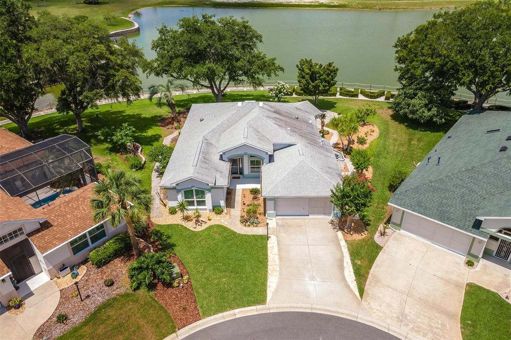An aerial view shows a suburban house with a gray roof, driveway, and backyard pond — 3354 SAINT LUCIA COURT, TAVARES, FL