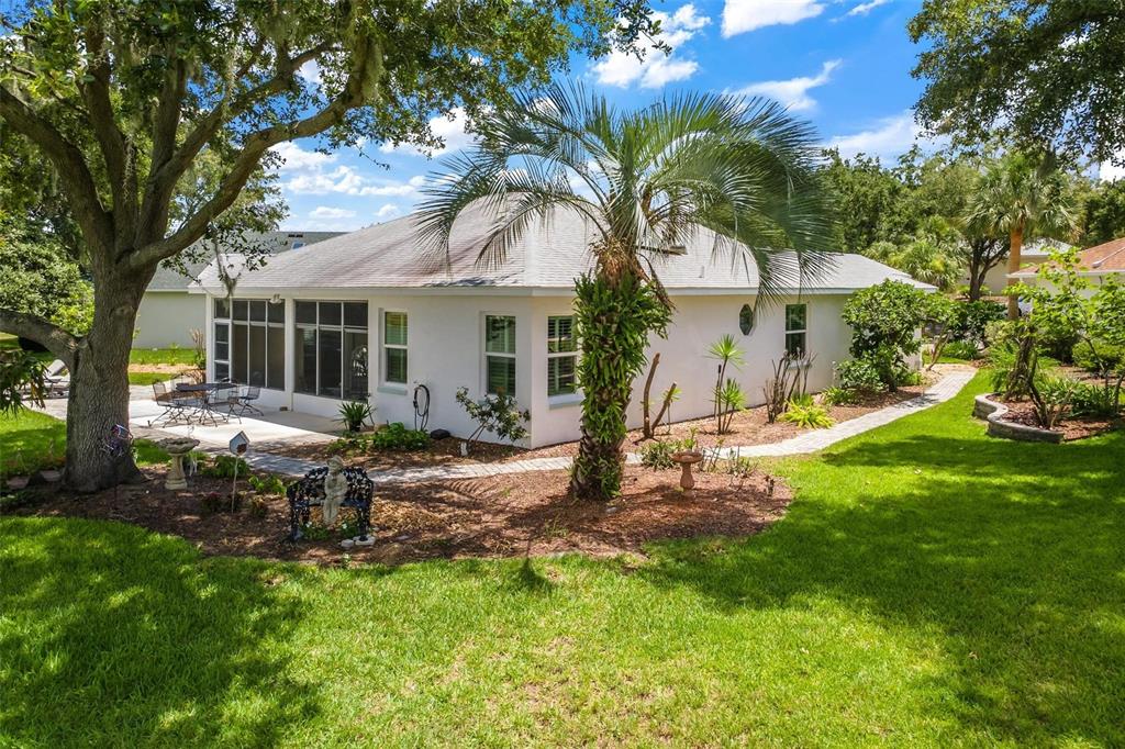 A white house with a screened-in patio, palm tree, and landscaped yard under a blue sky — 3354 SAINT LUCIA COURT, TAVARES, FL