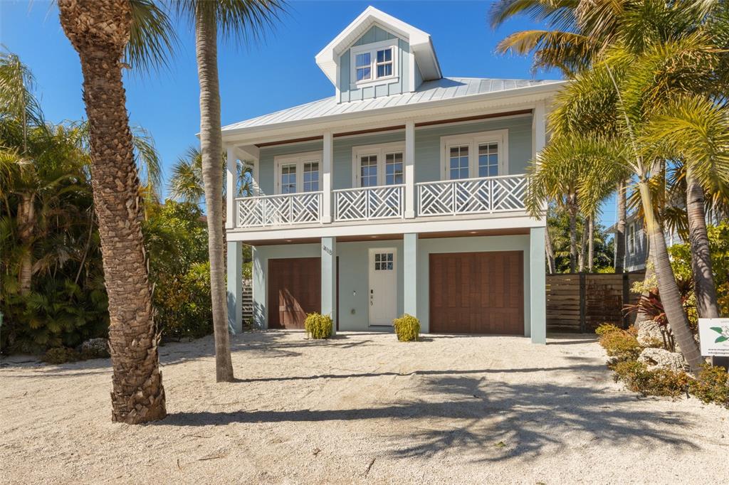 A light blue two-story house with a white balcony and two brown garage doors — 418 MAGNOLIA AVENUE, ANNA MARIA, FL
