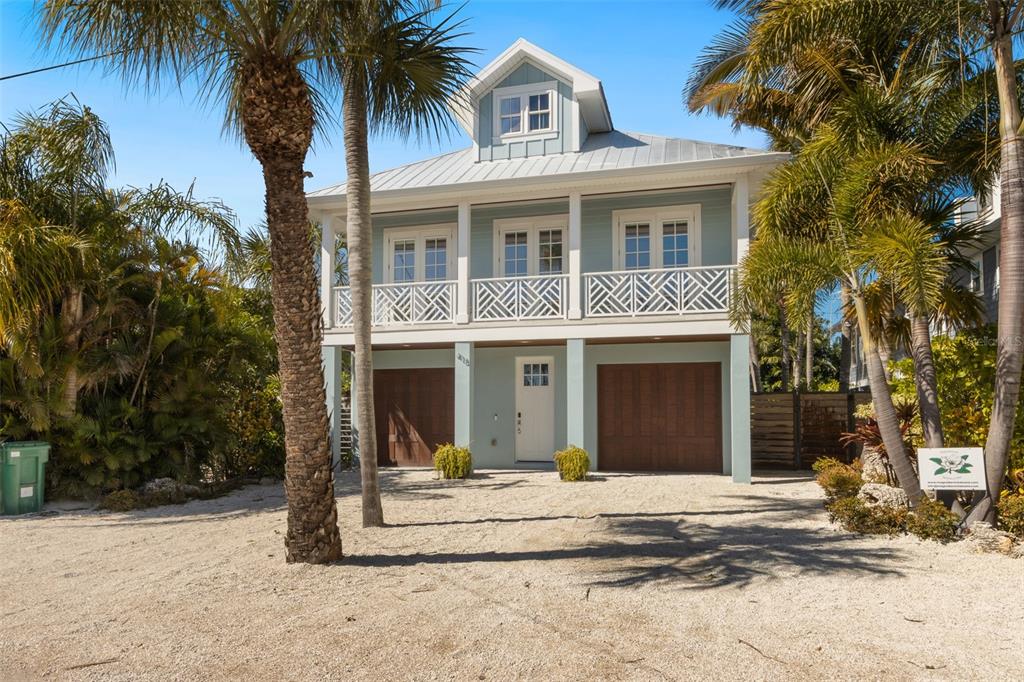 A two-story coastal house with a metal roof, balcony, and two garage doors — 418 MAGNOLIA AVENUE, ANNA MARIA, FL