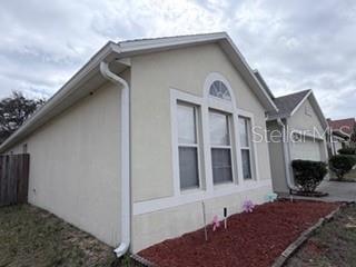 A side view of a beige stucco house with a white-trimmed arched window — 114 VERVAIN AVENUE, DAVENPORT, FL