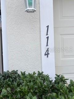 The number 114 is mounted vertically on a white exterior wall next to a garage door — 114 VERVAIN AVENUE, DAVENPORT, FL
