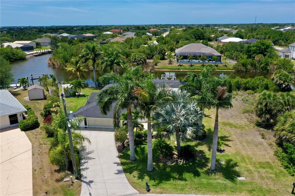 An aerial view of a suburban house with a driveway, palm trees, and a canal — 14494 LILLIAN CIRCLE, PORT CHARLOTTE, FL