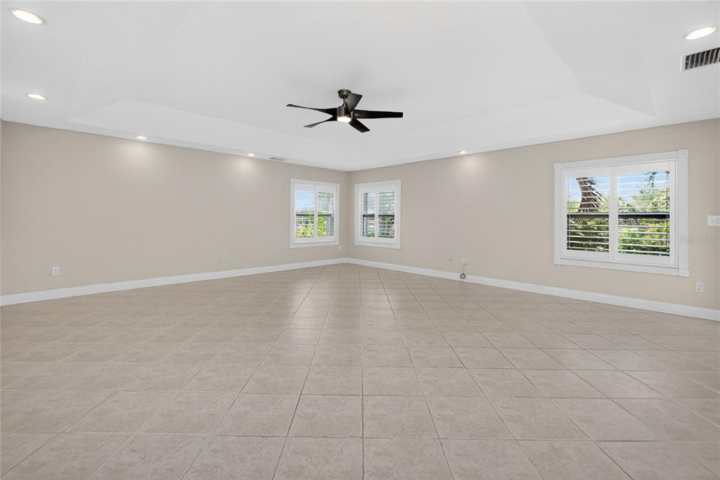 An empty room with beige tile flooring, a tray ceiling, and a ceiling fan — 14494 LILLIAN CIRCLE, PORT CHARLOTTE, FL