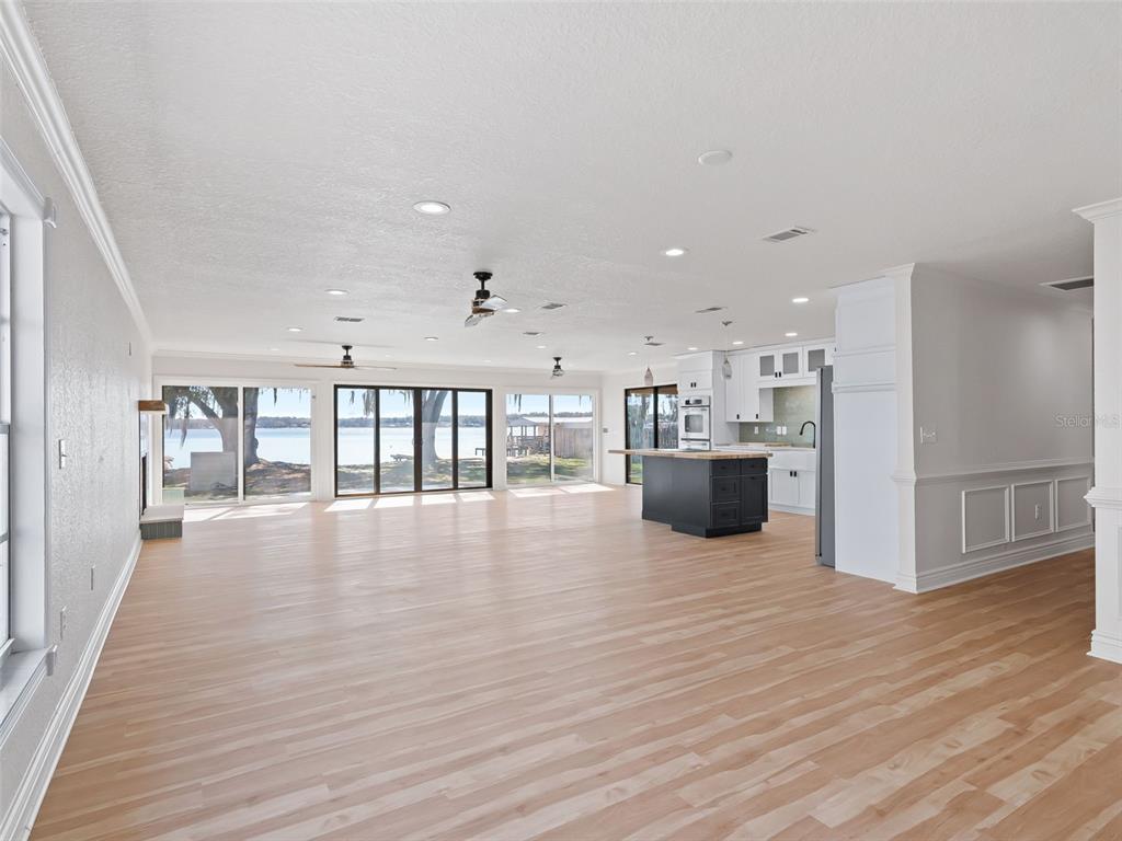 An open-concept living area features light wood flooring, a kitchen island, and large glass doors — 10916 SE TIMUCUAN ROAD, SUMMERFIELD, FL