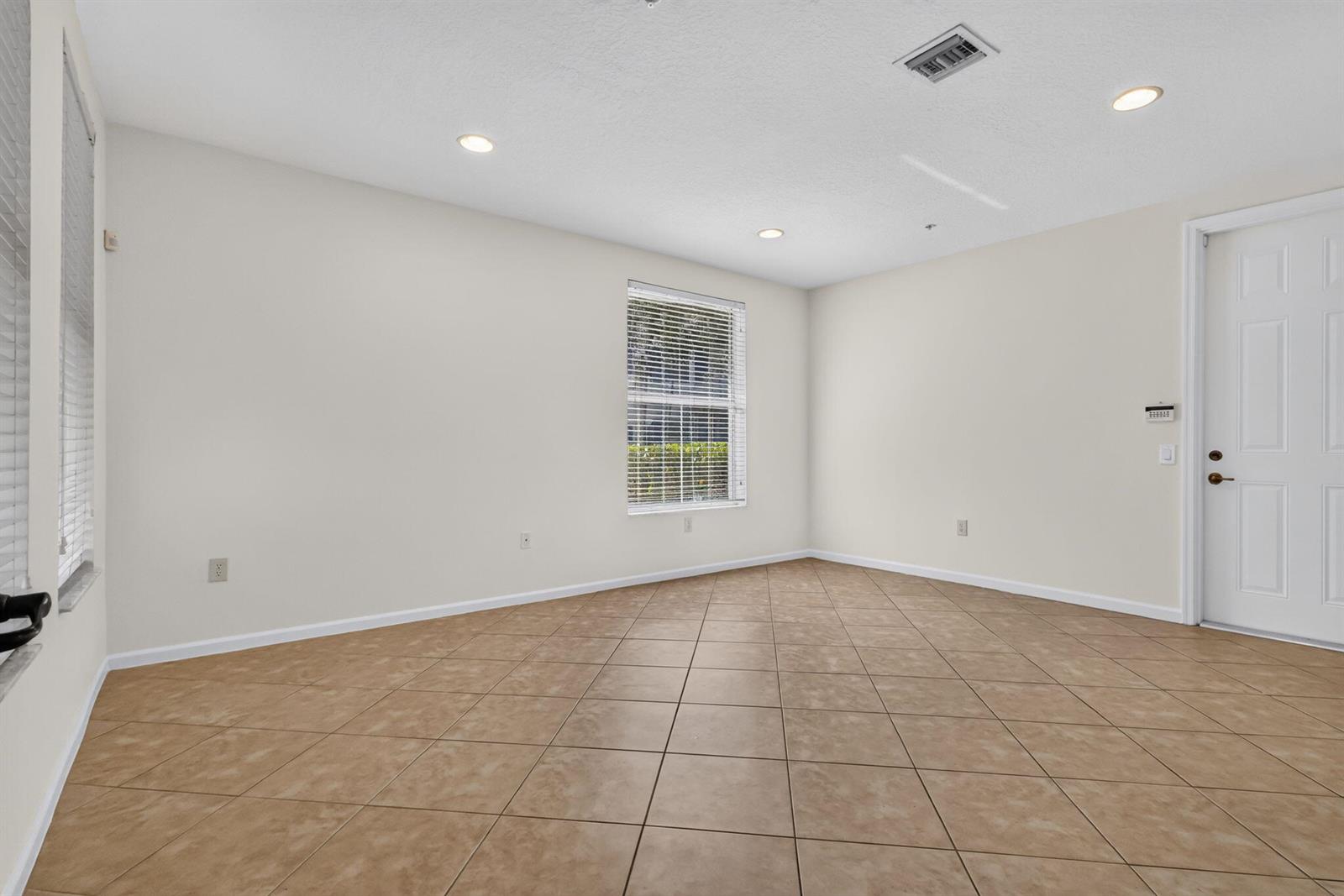 An empty room features beige tile flooring, white walls, recessed lighting, and two windows with blinds — 1213 Via Fatini, Boynton Beach FL 33426, BOYNTON BEACH, FL