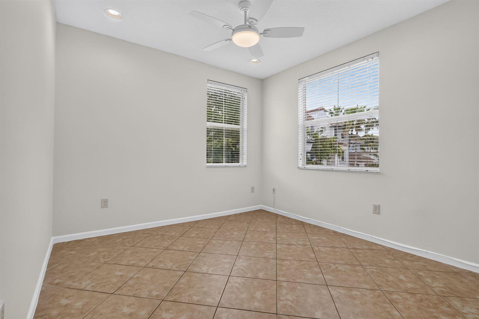 An empty room features light-colored walls, tile flooring, a ceiling fan, and two windows — 1213 Via Fatini, Boynton Beach FL 33426, BOYNTON BEACH, FL