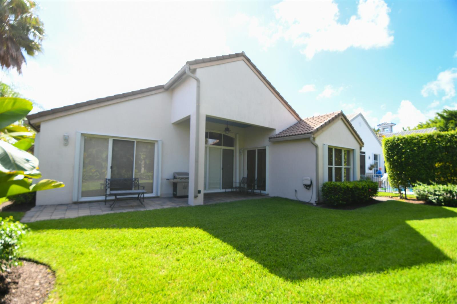 The exterior of a single-story house features a covered patio, lawn, and sliding glass doors — 8197 Cypress Point Road, West Palm Beach FL 33412, WEST PALM BEACH, FL