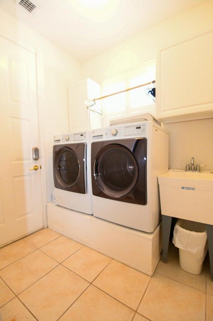 A laundry room features a washer and dryer on a platform, a utility sink, and tile — 8197 Cypress Point Road, West Palm Beach FL 33412, WEST PALM BEACH, FL