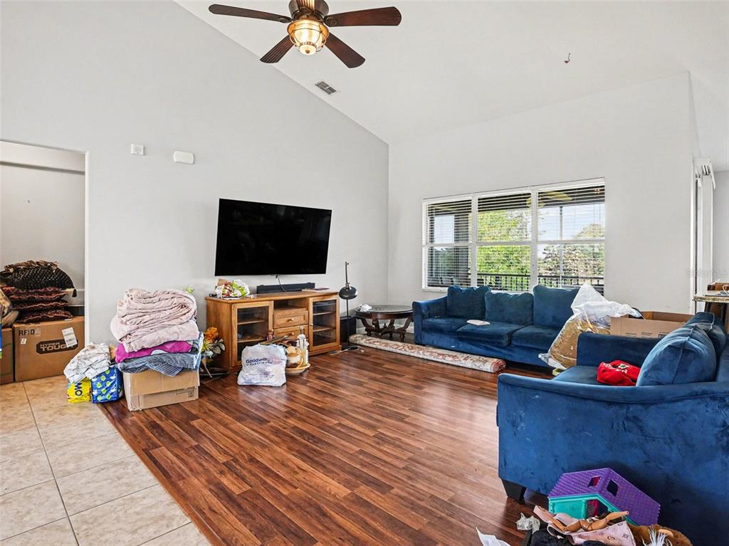 A living room features blue sofas, a wooden media console, and wood-look flooring — 1042 HARMONY LANE, CLERMONT, FL