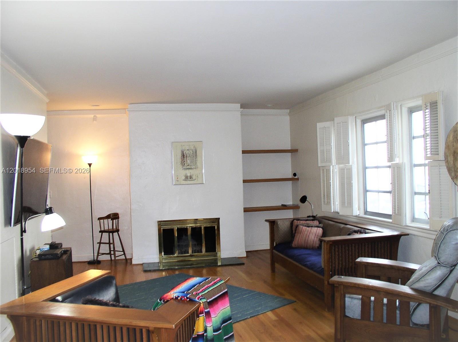 A living room features a fireplace, built-in shelves, hardwood floors, and wooden furniture — 404 Viscaya Ave # 404, Coral Gables FL 33134, CORAL GABLES, FL