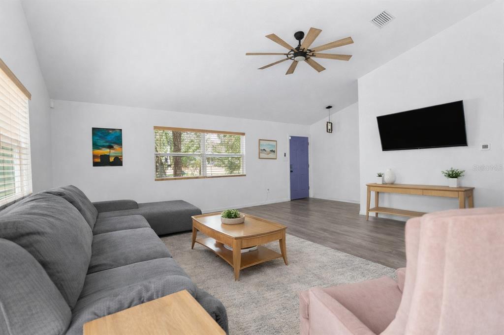 A living room features a grey sectional sofa, a wooden coffee table, and a purple door — 15236 MOTTLED OWL ROAD, BROOKSVILLE, FL