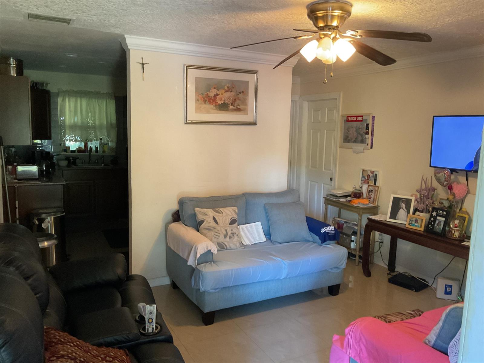 A living room features a blue sofa, a black leather recliner, and a wall-mounted television — 1433 NE 26th Court, Pompano Beach FL 33064, POMPANO BEACH, FL