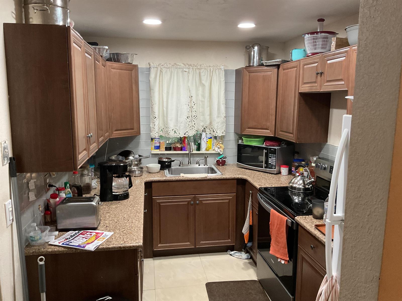 A small kitchen features wood cabinets, granite countertops, a stainless steel sink, and appliances — 1433 NE 26th Court, Pompano Beach FL 33064, POMPANO BEACH, FL
