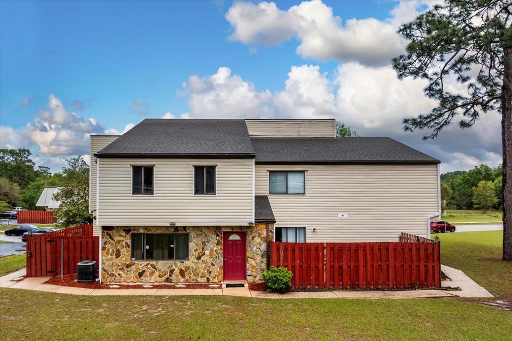 A two-story house with beige siding, a stone facade, and a red front door — 2134 NE 45TH AVENUE, OCALA, FL