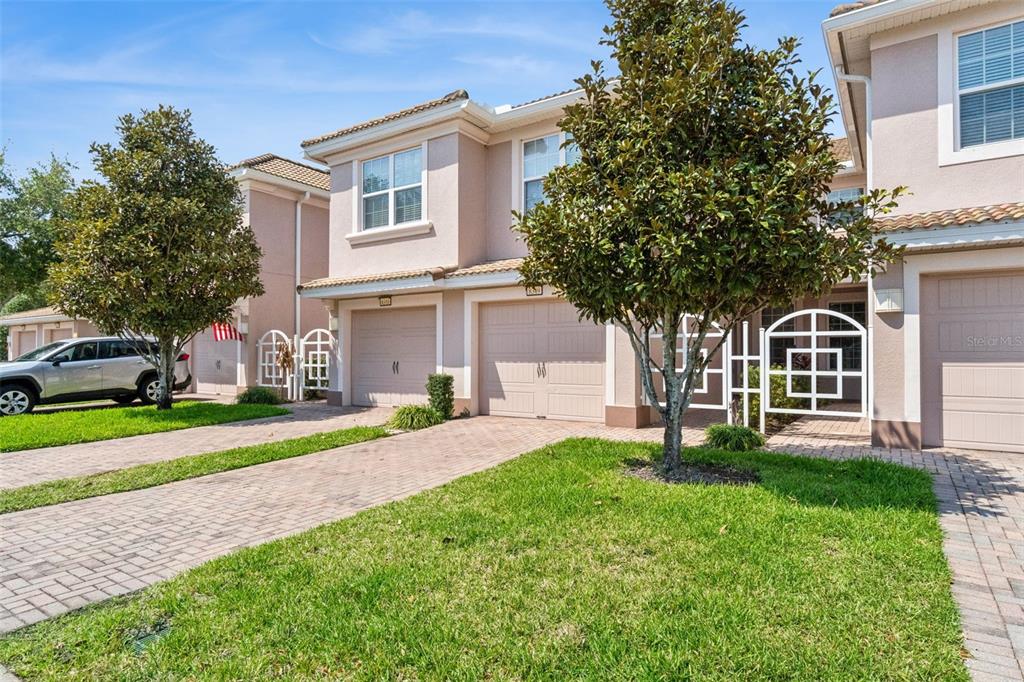 A row of two-story townhouses with beige stucco exteriors, tiled roofs, and paved driveways — 8349 BELLA TIERRA COURT, DAVENPORT, FL