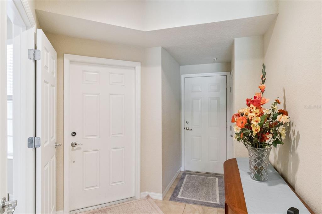 An entryway features two white doors, a tiled floor, and a floral arrangement on a table — 8349 BELLA TIERRA COURT, DAVENPORT, FL