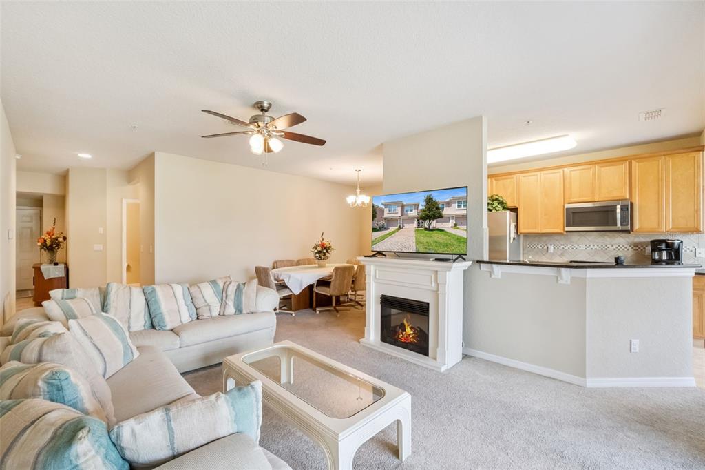 A living room features a fireplace, a television, a dining area, and an open kitchen — 8349 BELLA TIERRA COURT, DAVENPORT, FL
