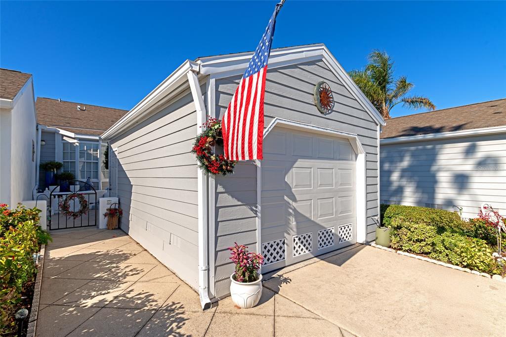 A gray detached garage with a white door, American flag, and decorative wreath — 504 WOODSTORK CIRCLE, BRADENTON, FL
