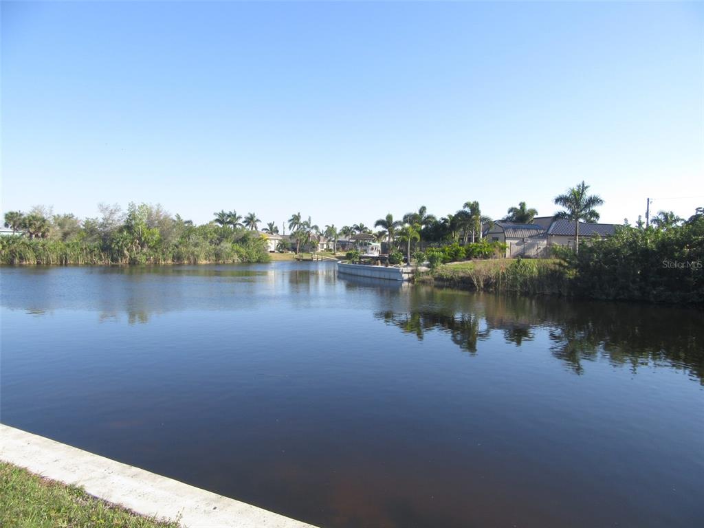 A view of a calm canal bordered by a concrete seawall and residential landscaping — 9572 SINGER CIRCLE, PORT CHARLOTTE, FL