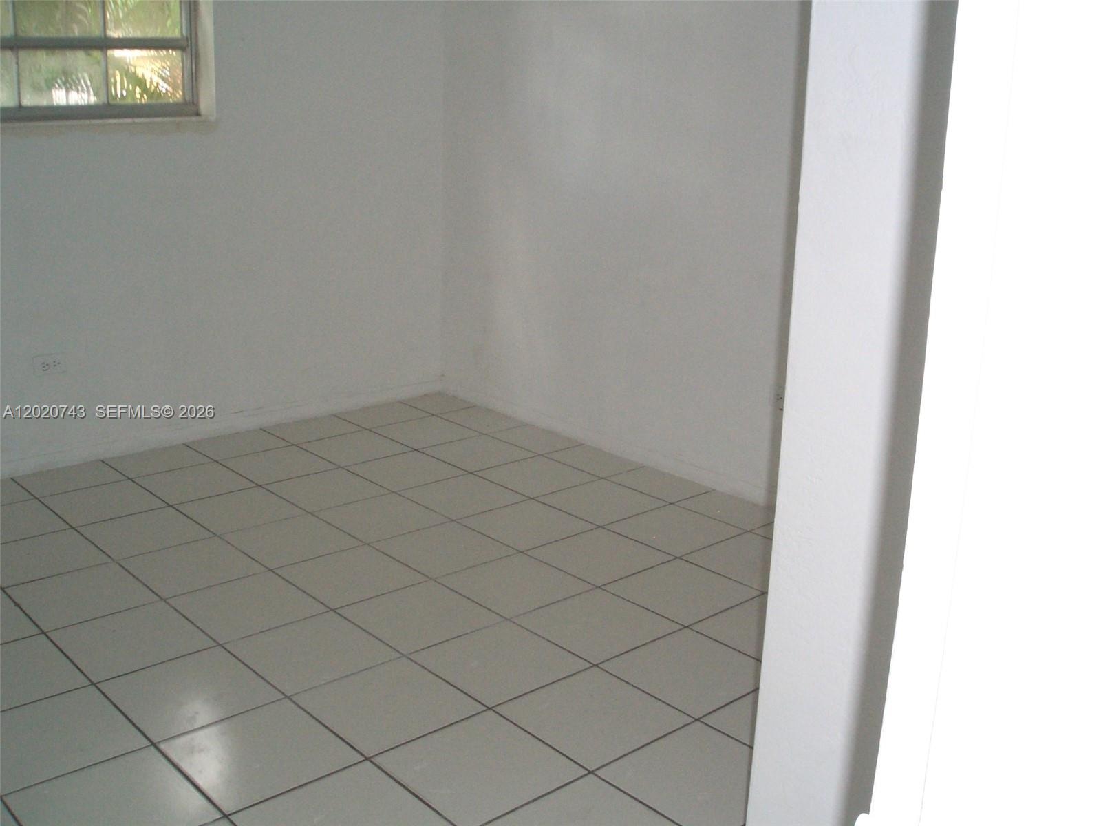 An empty room features white walls, a single window, and light-colored square floor tiles — 9760 SW 184th St # 16D, Cutler Bay FL 33157, CUTLER BAY, FL