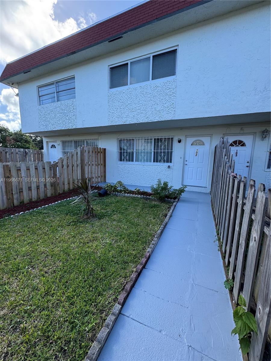 The exterior of a two-story residential building features white stucco walls and a red roof — 1481 NE 150th St # 102, Miami FL 33161, MIAMI, FL