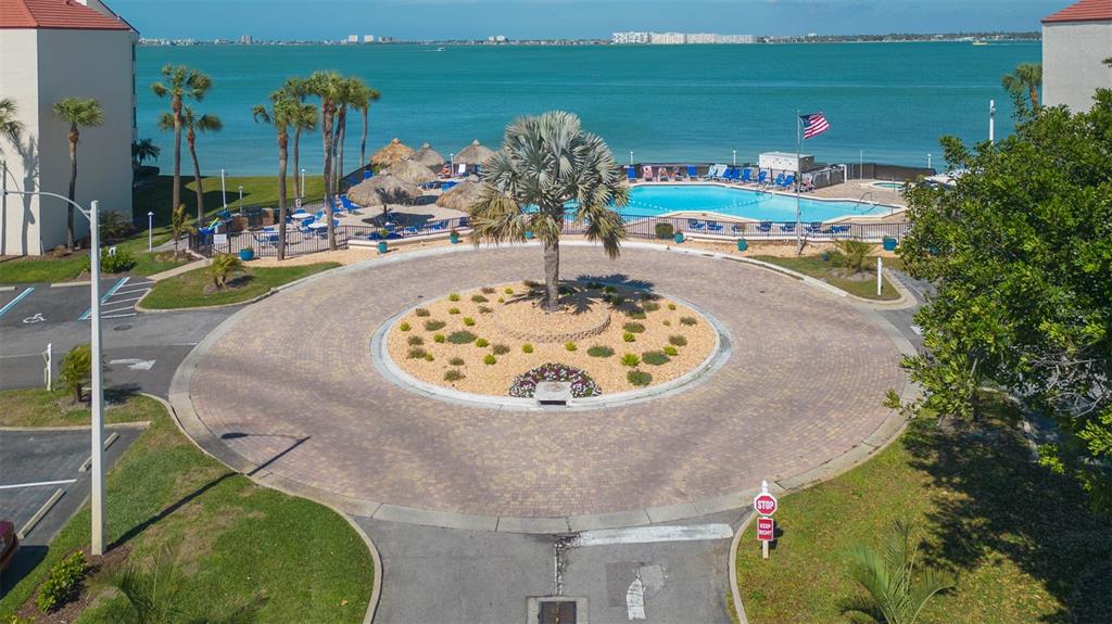 An aerial view of a circular paved driveway with a central palm tree and pool — 5633 PUERTA DEL SOL BOULEVARD S UNIT 204, ST PETERSBURG, FL