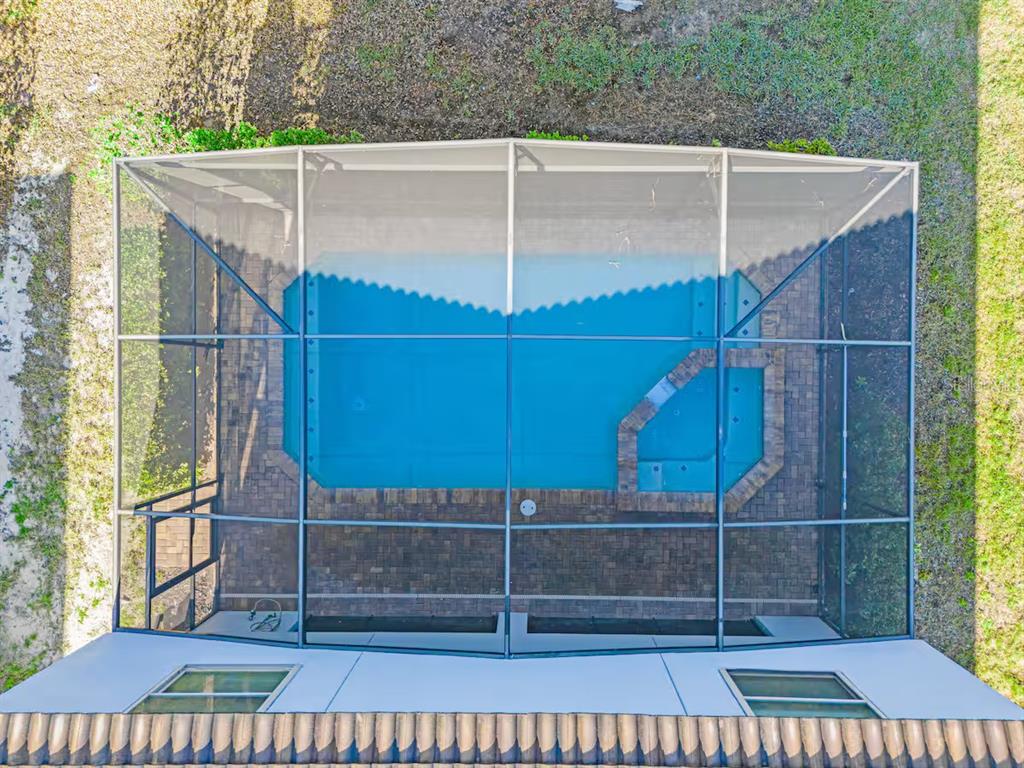 An aerial view shows a rectangular swimming pool and spa enclosed by a screened lanai — 5405 MISTY OAK CIRCLE, DAVENPORT, FL
