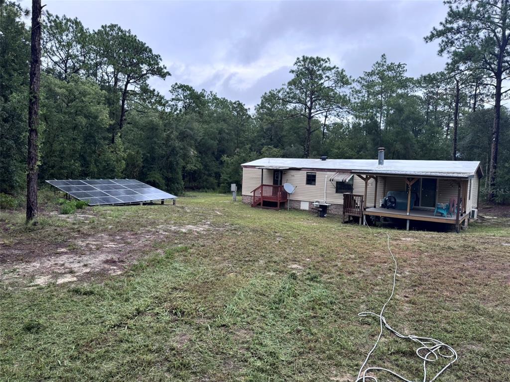 A mobile home with a ground-mounted solar panel array sits on a wooded lot — 13322 SW 95TH STREET, DUNNELLON, FL