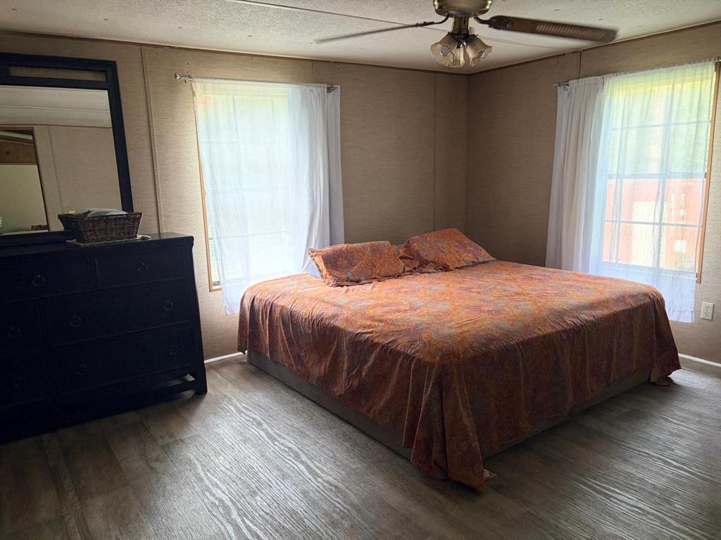 A bedroom with wood-look flooring, a ceiling fan, a dark dresser, and a patterned bedspread — 13322 SW 95TH STREET, DUNNELLON, FL
