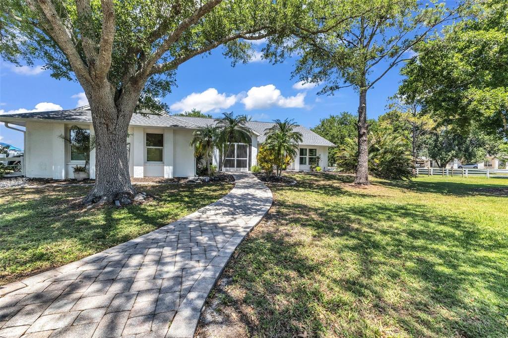 A screened-in swimming pool with a brick paver deck and palm trees in the background — 5222 BLACKJACK CIRCLE, PUNTA GORDA, FL