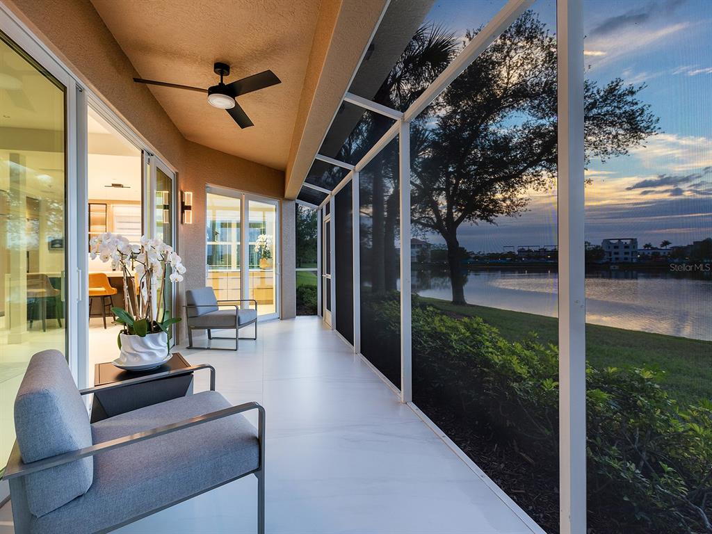 A screened-in patio features tile flooring, a ceiling fan, and views of a lake — 6427 MOORINGS POINT CIRCLE UNIT 101, LAKEWOOD RANCH, FL