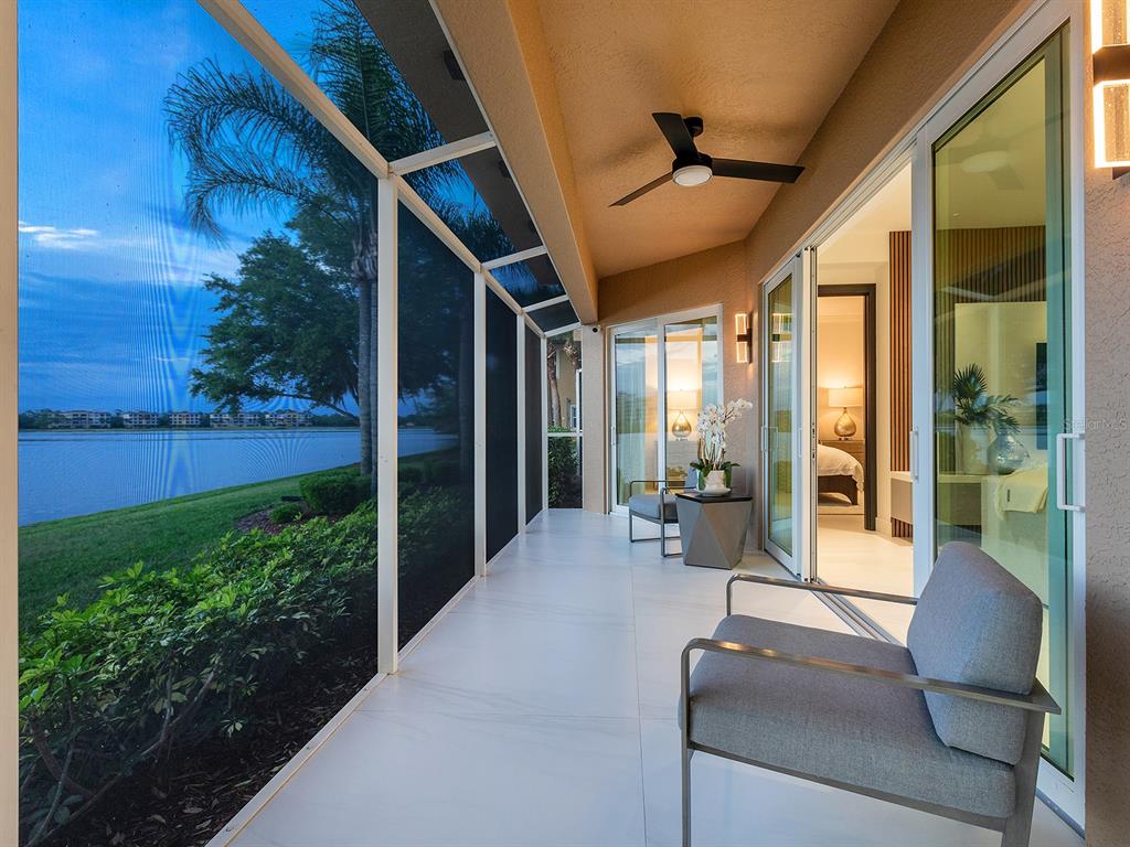 A covered patio with tile flooring, a ceiling fan, and a view of a lake — 6427 MOORINGS POINT CIRCLE UNIT 101, LAKEWOOD RANCH, FL