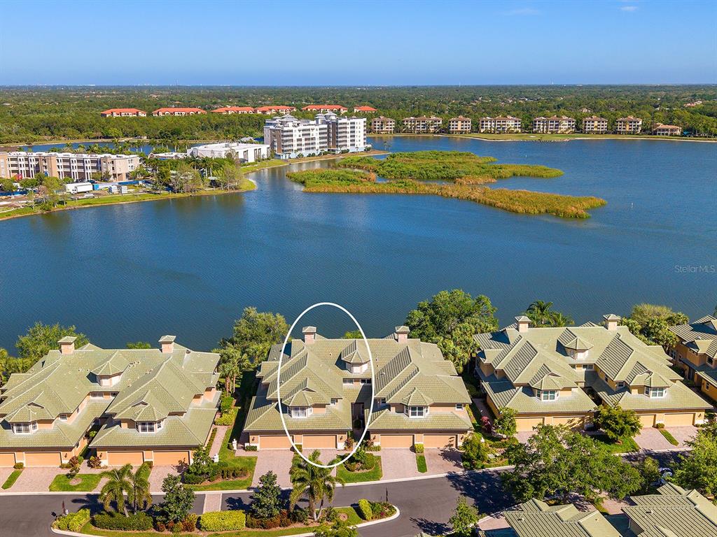 An aerial view shows a multi-story residential building with a green roof near water — 6427 MOORINGS POINT CIRCLE UNIT 101, LAKEWOOD RANCH, FL
