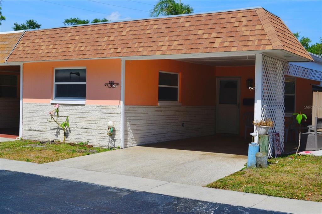 A single-story house with a peach-colored exterior, a stone-textured base, and an attached carport — 331 SKY LOCH DRIVE W, DUNEDIN, FL