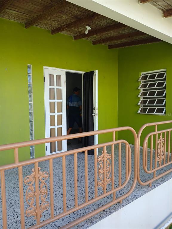 A lime green porch features a white French door, a jalousie window, and metal railings — 600 Pascual Valle CALLE PASCUAL VALLE CASTILLO, MAYAGUEZ, PR