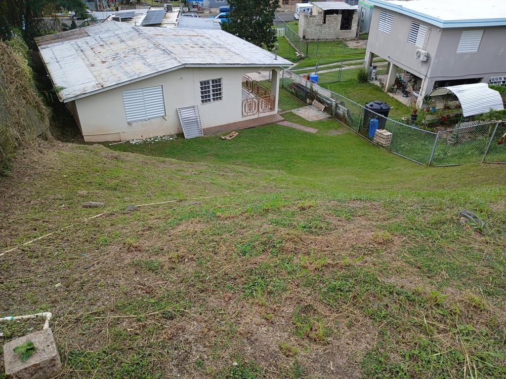 A sloped grassy yard overlooks a single-story house with a metal roof and a porch — 600 Pascual Valle CALLE PASCUAL VALLE CASTILLO, MAYAGUEZ, PR