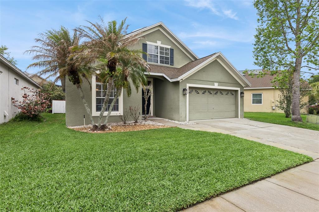 A two-story house with a green stucco exterior, a two-car garage, and a palm tree — 520 TUTEN TRAIL, ORLANDO, FL