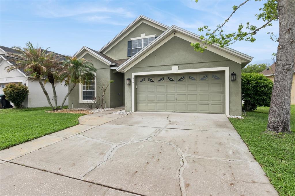 A green single-story house with a two-car garage and a cracked concrete driveway — 520 TUTEN TRAIL, ORLANDO, FL