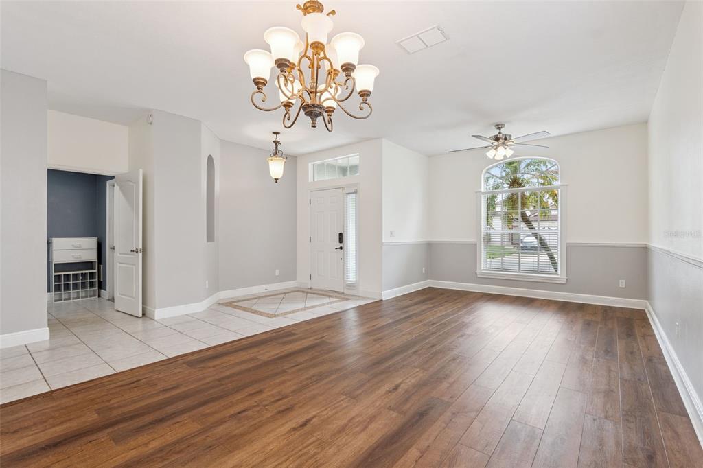 A bright living room features wood-look flooring, a chandelier, and a large arched window — 520 TUTEN TRAIL, ORLANDO, FL