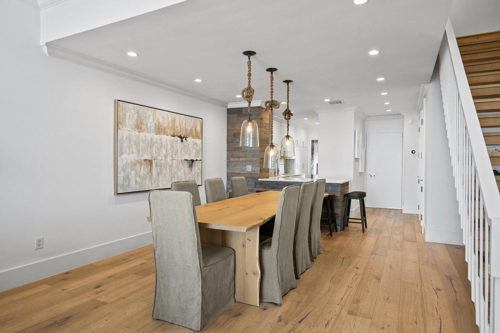 A dining area features a wooden table, slipcovered chairs, rope pendant lights, and wood flooring — 400 S Ocean Boulevard # 216, Palm Beach FL 33480, PALM BEACH, FL