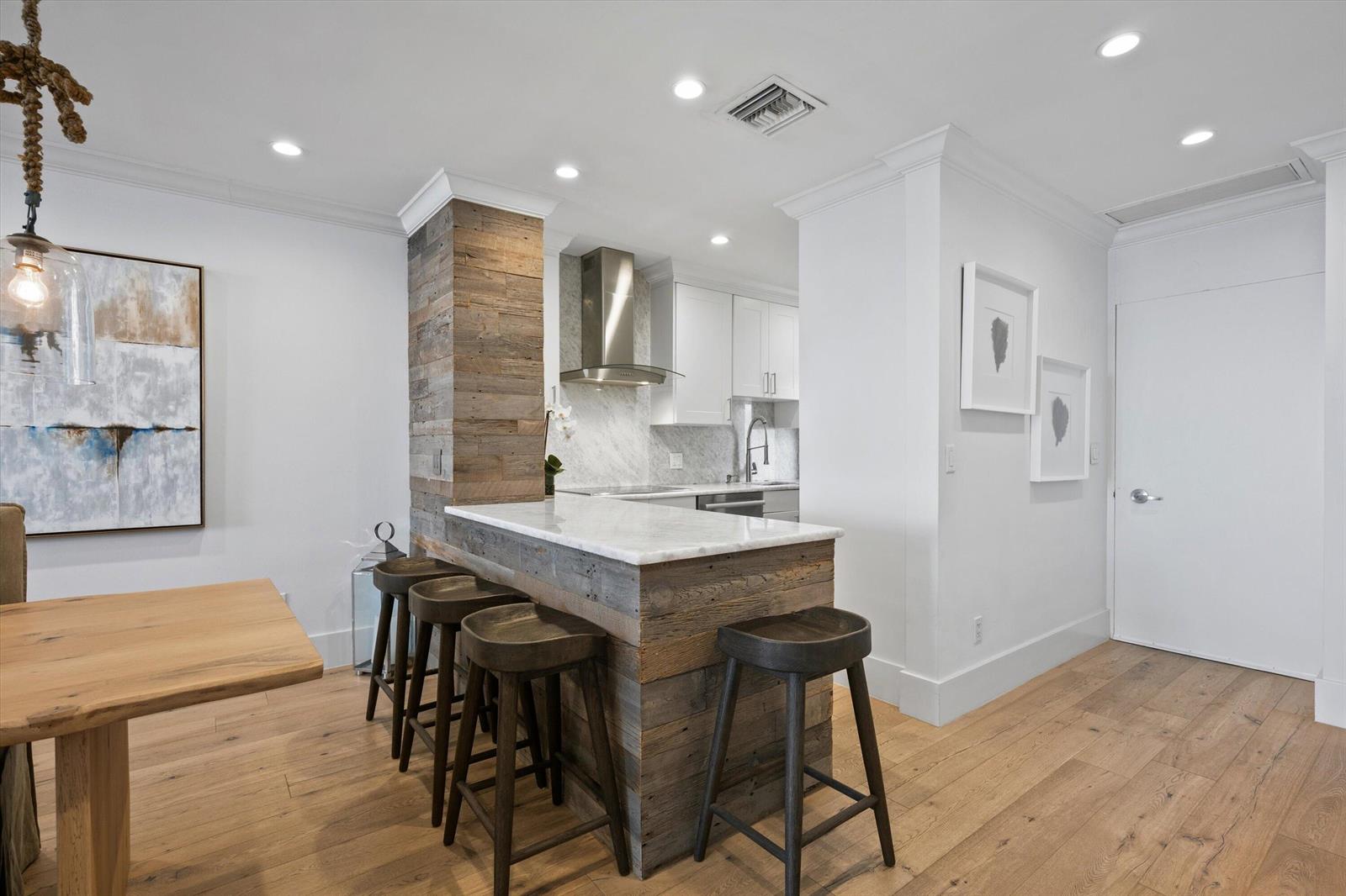A kitchen features a marble-topped breakfast bar with reclaimed wood siding and four wooden stools — 400 S Ocean Boulevard # 216, Palm Beach FL 33480, PALM BEACH, FL