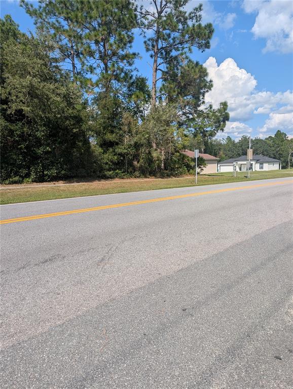A paved road runs in front of a wooded lot and a distant house — 3515 W CENTURY BOULEVARD, CITRUS SPRINGS, FL