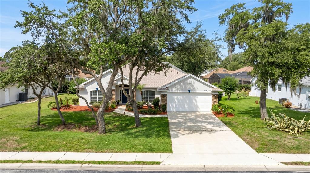 A single-story house with a white garage, light-colored siding, and large oak trees in front — 736 ALDENWOOD TRAIL, NEW SMYRNA BEACH, FL