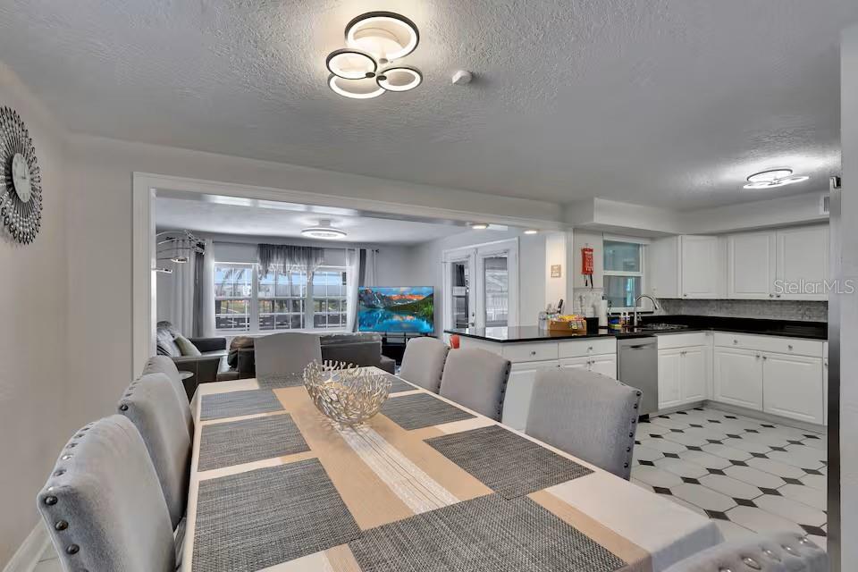 A dining area with a table and chairs opens into a kitchen and living room — 10712 DALTON AVENUE, TAMPA, FL