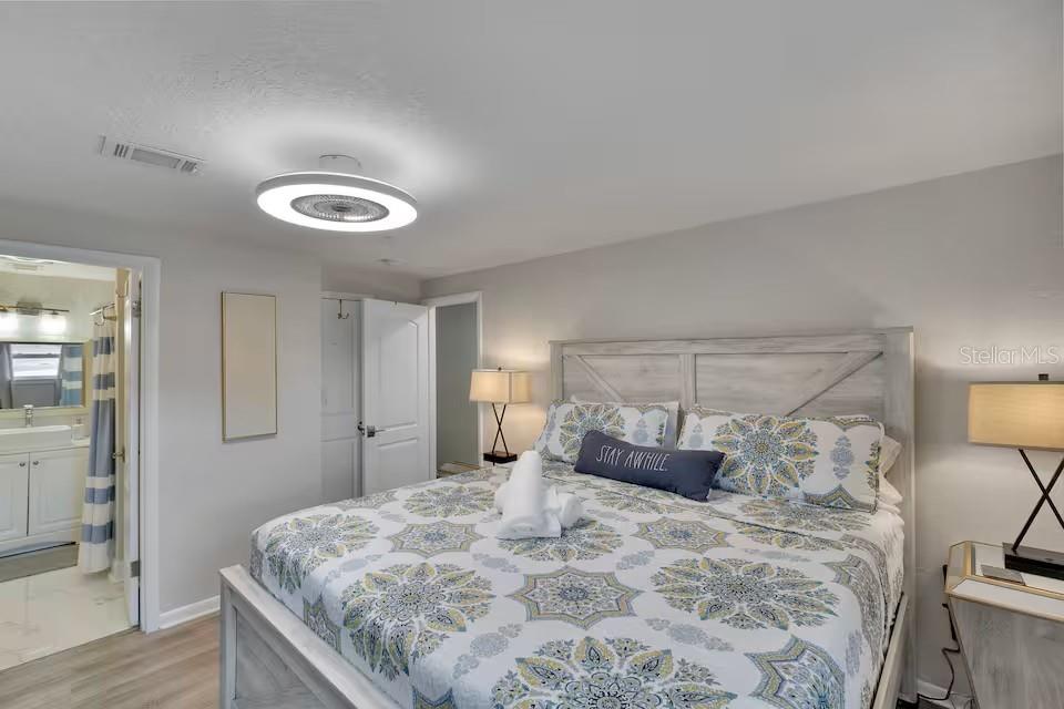 A bedroom features a bed with patterned bedding, a ceiling fan light, and an attached bathroom — 10712 DALTON AVENUE, TAMPA, FL